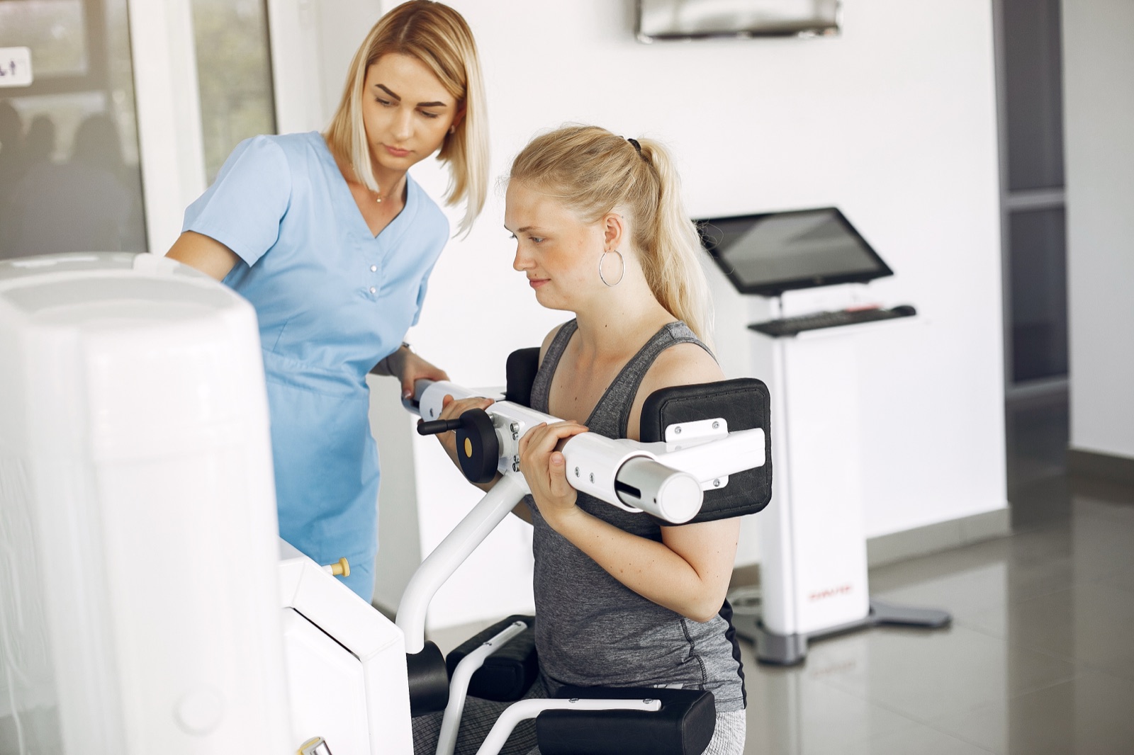A medical fitness professional guiding a client using specialised exercise equipment